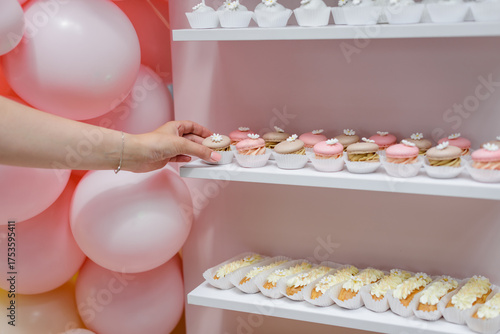 A hand reaching for a delicious macaron from a beautiful dessert display.