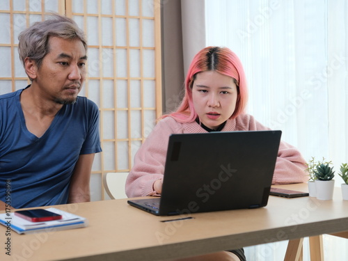 A woman with pink hair is typing on a laptop