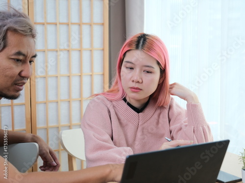 A woman with pink hair is typing on a laptop