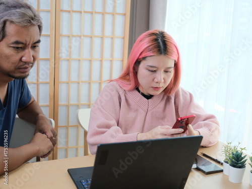 A woman with pink hair is typing on a laptop
