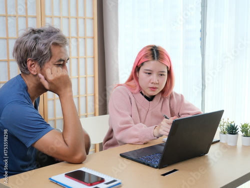A woman with pink hair is typing on a laptop