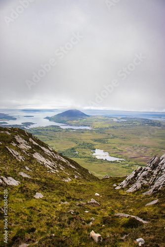 Slika na platnu Sweeping aerial view of a rugged, verdant landscape with a majestic mountain dominating the horizon under a cloudy sky