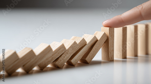 Finger stopping a domino chain reaction to represent prevention control and risk management in decision making and the power of timely intervention to stabilize outcomes.
