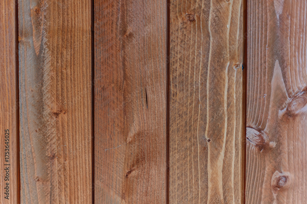 Fototapeta premium Close-up of natural wooden wall panels with visible grain and texture. The warm-toned wood surface highlights rustic and organic design elements.