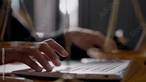 A person is typing on a laptop. The person is wearing a black shirt. The laptop is on a wooden table