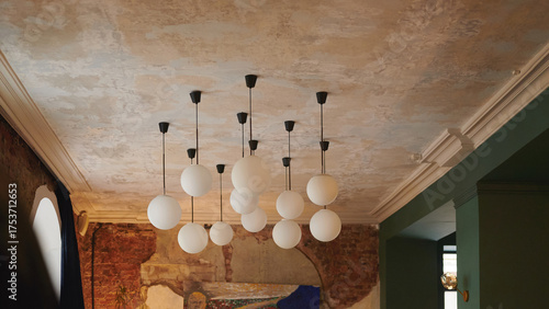 modern chandelier lighting enhances rustic interior with vintage brick wall and artistic painting. perfect scene for coffee shop, urban apartment, or cozy restaurant inspiration
