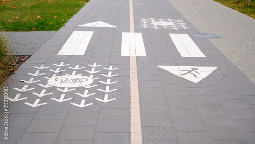 bicycle and pedestrian path markings show designated areas for bikes and walkers on tiled urban sidewalk. clear signage directs traffic flow, ensuring safety and organization
