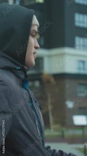 Close-up of athlete juggling soccer ball during training in urban sport arena, demonstrating focus and skill against blurred background of modern buildings and people walking in the distance
