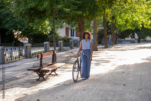 Young woman walking vintage bicycle in park