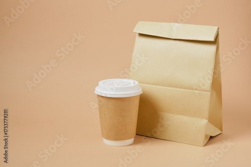 cup coffee and paper bag on beige background Coffee and takeaway, mockup, fast food, eco-friendly packaging