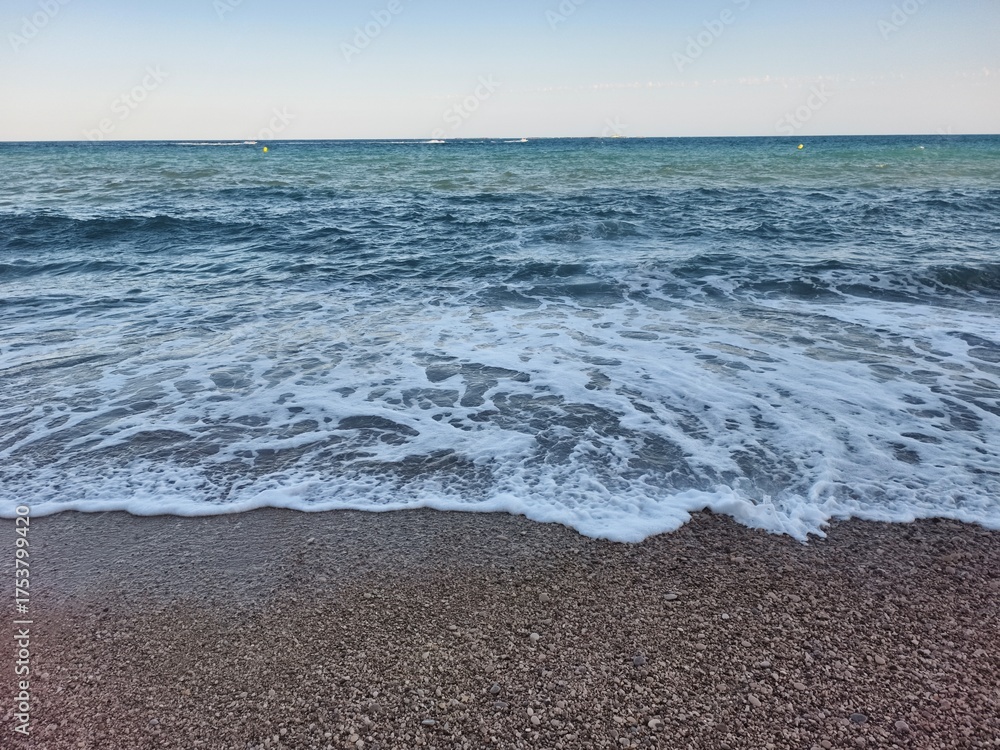 Obraz premium Serene Seaside Waves Gently Rolling In at Dawns Light, Creating a Peaceful Atmosphere