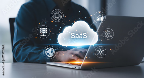 Businessperson working on a laptop with a glowing SaaS cloud icon and digital network connections overlaying the image representing cloud computing and software as a service technology