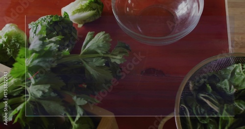 Showing bunch of parsley on red cutting board beside glass mixing bowl in kitchen, copy space