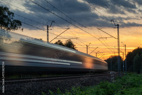 a speeding train blurred in the light of the setting sun