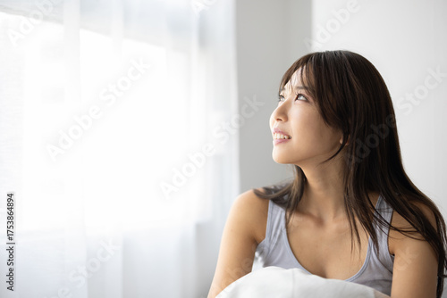 Young Woman Smiling in Morning Sunlight While Sitting Up in Bed Free Download Young Woman Smiling in Morning Sunlight While Sitting Up in Bed - GFXLoad