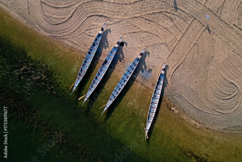 Rowboats (dragon boat) sitting still on the shore of a lake