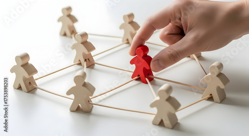 Hand places red figure into connected network of wooden people figures