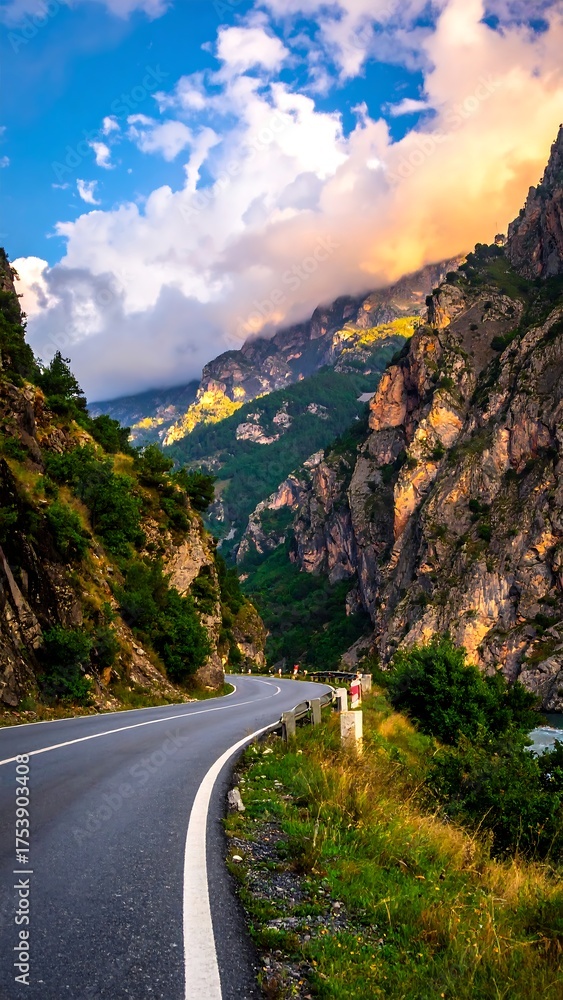 Fototapeta premium A winding road journeys through a dramatic mountain gorge, bathed in sunset light