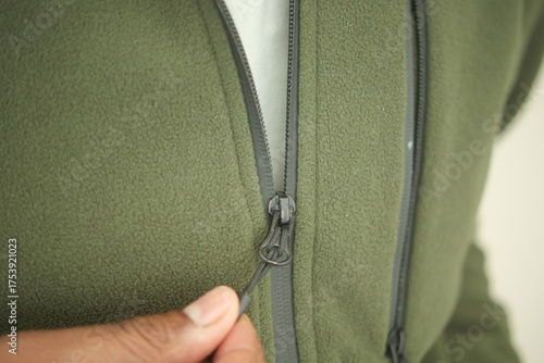 Fotografie Close-up of hands zipping a green fleece jacket