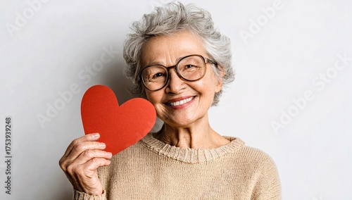 Portrait of old adult blonde caucasian glad lady holding hands big red paper heart shape