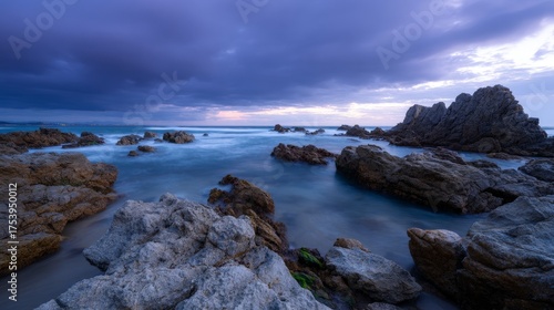 Dramatic twilight over rocky coastal landscape with moody sky and ocean waves
