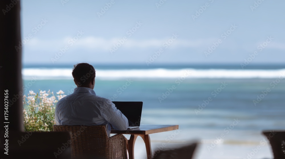 Obraz A male remote worker at a beachside cafe with his laptop, enjoying the digital nomad lifestyle.