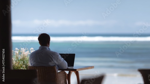 A male remote worker at a beachside cafe with his laptop, enjoying the digital nomad lifestyle.
