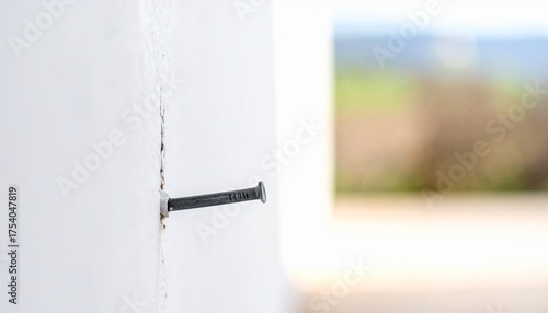 Nail Embedded in White Wall, Blurry Background