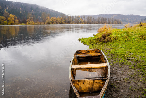Wallpaper Mural Experience a serene autumn landscape with a wooden boat floating on a calm river, surrounded by vibrant foliage and picturesque scenery that captures relaxation and exploration in natures beauty Torontodigital.ca