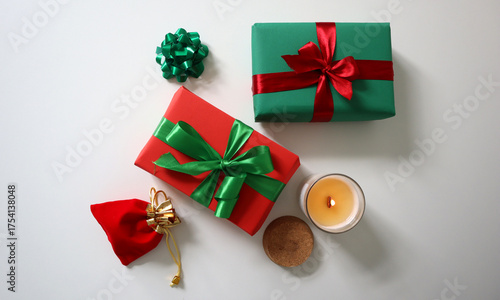 Festive gifts wrapped in red and green paper with satin ribbons, a holiday pouch, and a lit soy candle on a white background. Perfect for Christmas, New Year, and holiday promotions. Christmas colors.