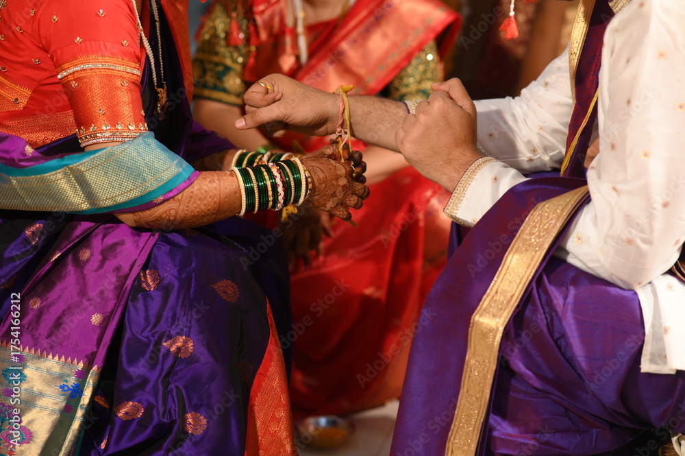 Fototapeta premium Indian bride Tie a Turmeric Thread Yellow knot on hand of groom. Close Up Hands of bride and Groom in hindu wedding. Marathi Wedding Ceremony. Maharashtra Culture. Hindu wedding. indian wedding couple