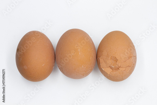 two whole eggs and one broken egg are lying in a row on a white background