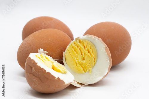 a boiled egg is cut in half, showing the texture of the white and yolk against the background of other whole eggs on a white background
