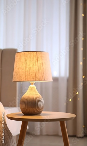 Cozy Bedroom Scene with Modern Ceramic Table Lamp Illuminating a Small Wooden Nightstand Beside Soft Curtains and Warm String Lights for Home Interior and Relaxation Concept