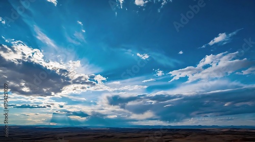 Vast desert landscape under a dramatic sky, with sun rays piercing through scattered clouds, evoking awe and serenity.