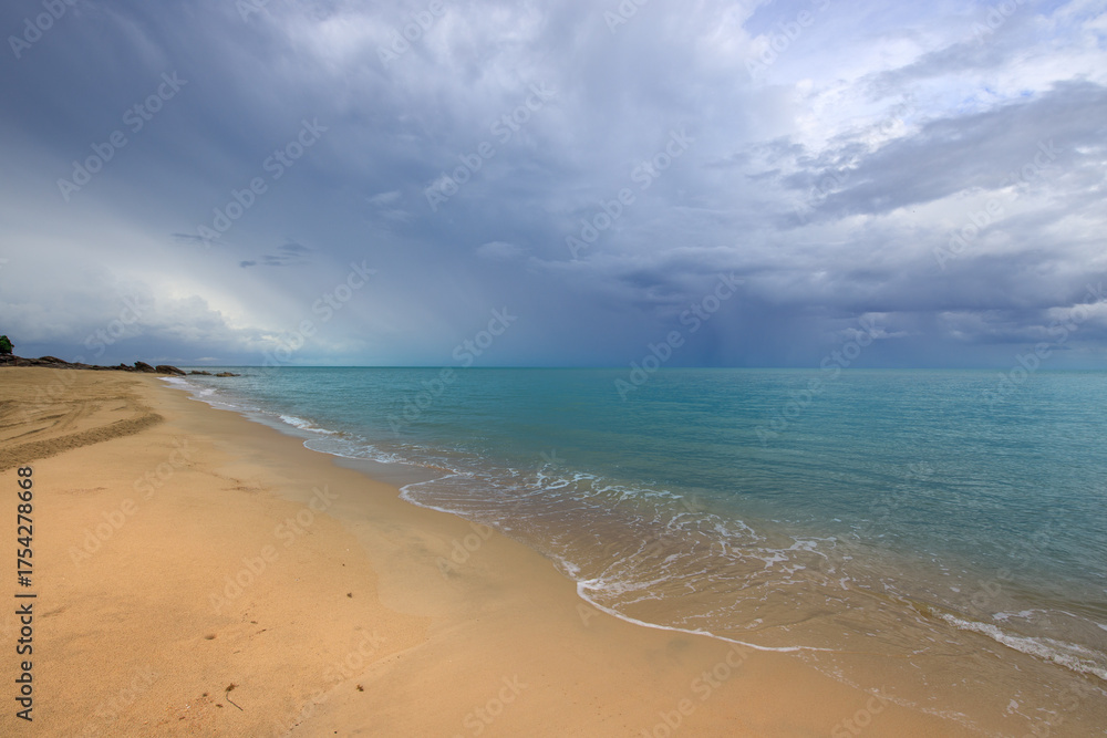 Fototapeta premium Beach with a cloudy sky in the background