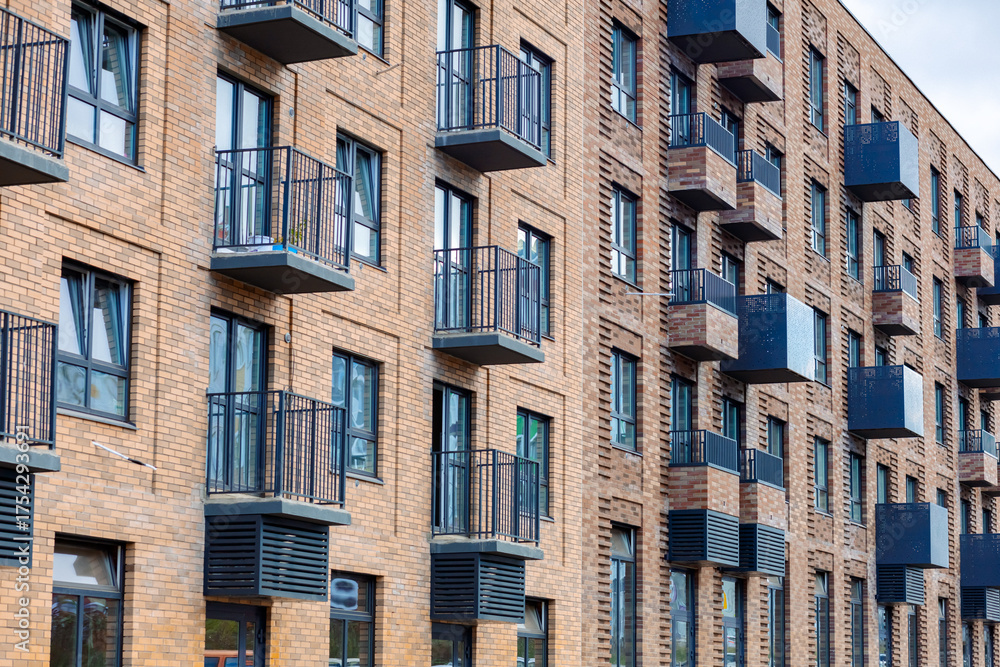 Obraz premium A modern loft-style residential complex. Brick walls, large windows, and balconies with metal railings. The architecture emphasizes comfort and style.