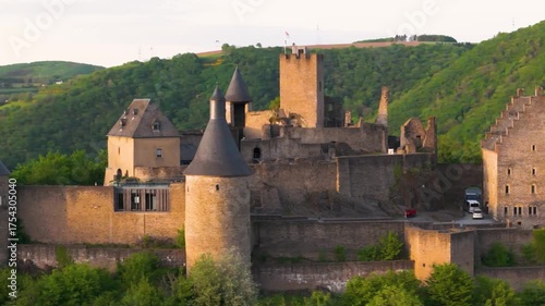bourscheid castle château de green valley cover hills behind walls towers exterior views visitor parking vehicles to left near right up close circling drone 