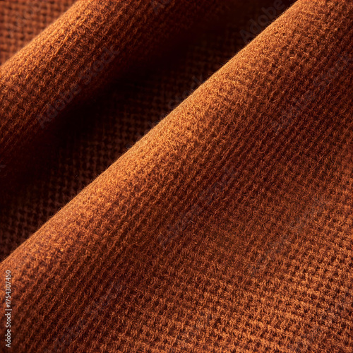 close up of folded woven nutmeg coloured fabric with shadows in the folds. 