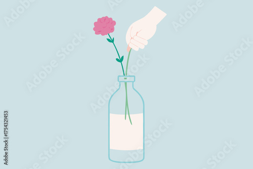 Hand placing a flower in a glass bottle