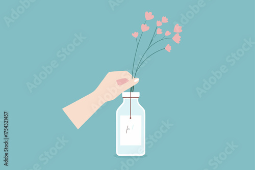Hand holding flowers in a glass bottle