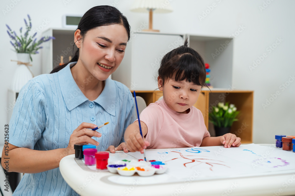 Fototapeta premium happy mother and toddler girl painting watercolor in paper at home