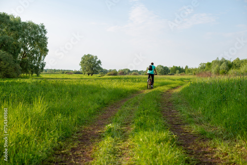 Foto A person riding a bicycle on a grassy path in the countryside.