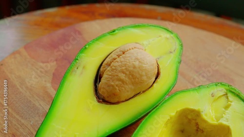 Slow pull out and slide movement of a sliced avocado, placed on a wooden cutting board, with shallow depth of field