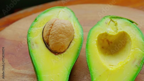 Slow pull out and slide movement of a sliced avocado, placed on a wooden cutting board, with shallow depth of field