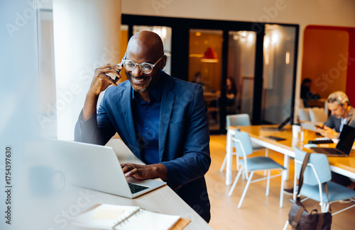 Businessman on a phone call working on a laptop in an office setting