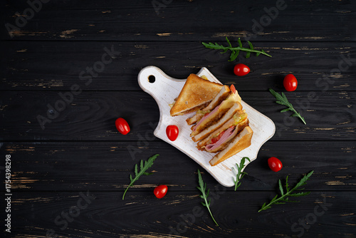 Club sandwich with ham, tomatoes, cheese and herbs. Toasts with filling