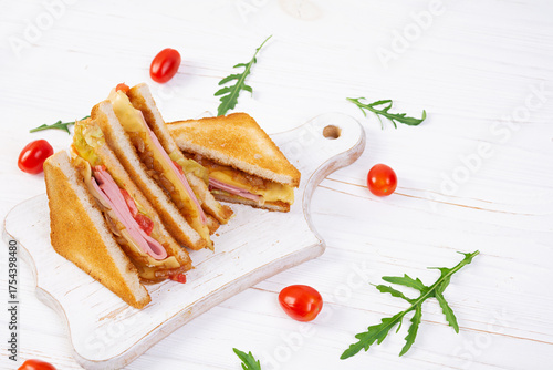 Club sandwich with ham, tomatoes, cheese and herbs. Toasts with filling