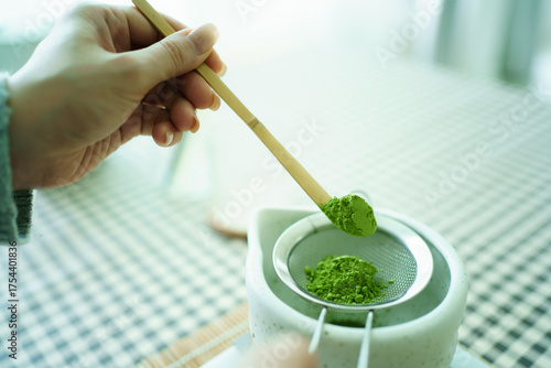 Foto Woman sifting matcha powder into bowl on digital scale.