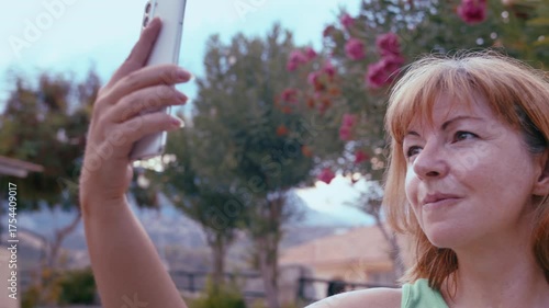 Young Woman Taking Selfie with Mobile Phone While Standing Outdoors in Scenic Nature Landscape